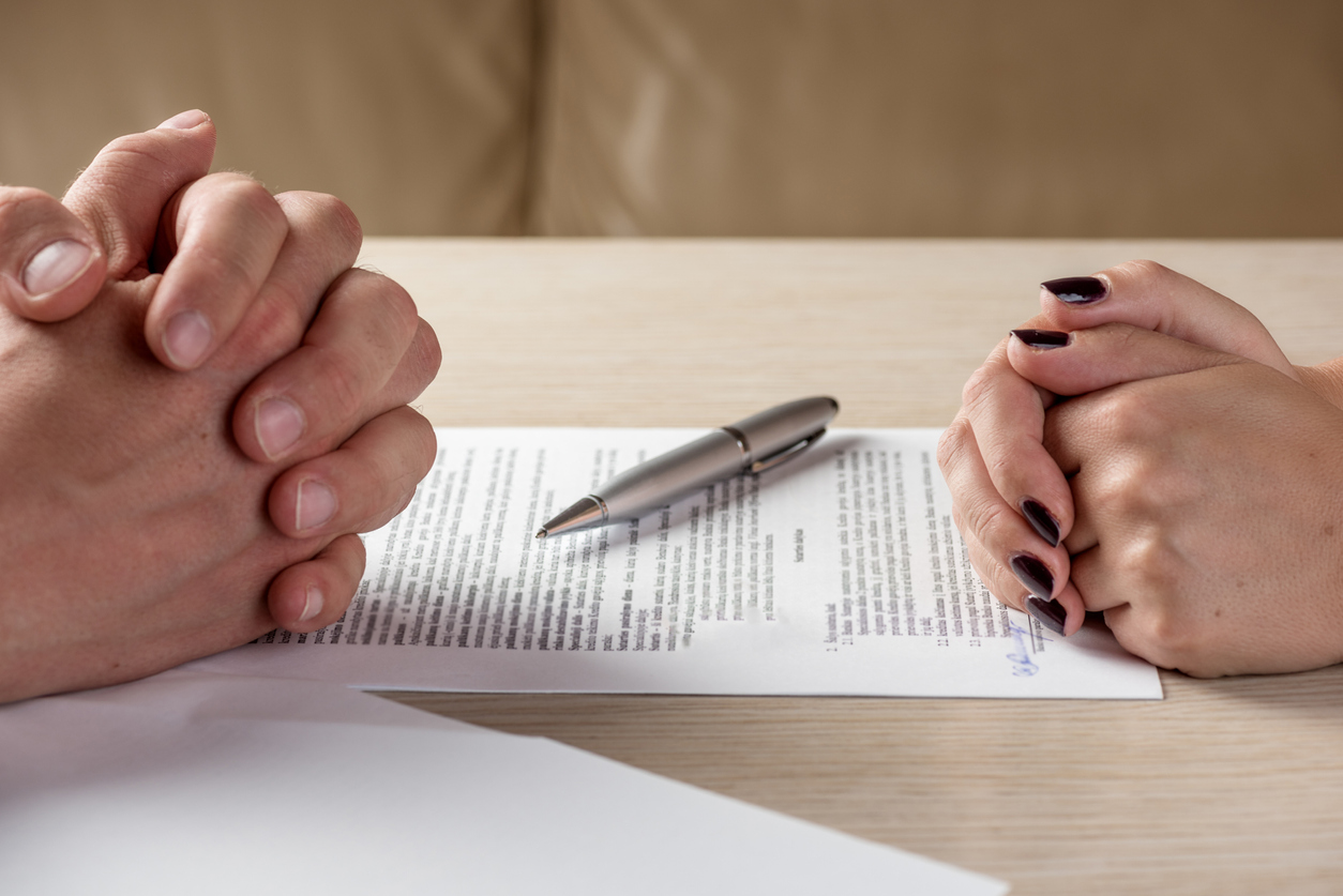 Hands of contractual parties, a woman and a man, signing a contract